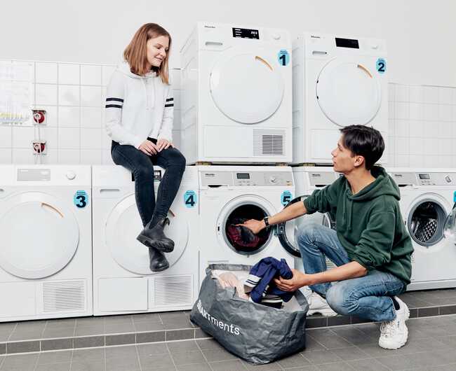 Zwei Studenten unterhalten sich angeregt im Waschsalon